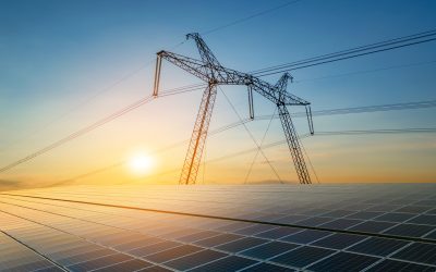 High voltage pylons with electric power lines transfering electricity from solar photovoltaic sells at sunrise. Production of sustainable energy concept.