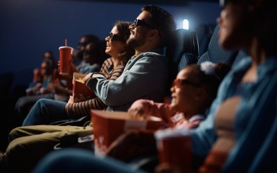 Happy couple wearing 3D eyeglasses while watching movie in theater.