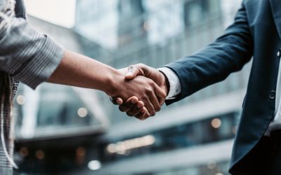 Meeting success. Two business persons shaking hands standing outside