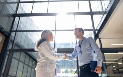 Medical sales representative greeting a doctor with a handshake at the hospital and smiling - healthcare and medicine concepts