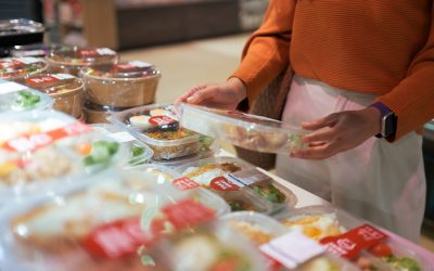 Customer selecting a convenient grab and go bento box from a supermarket deli, offering quick lunch and dinner meal solutions