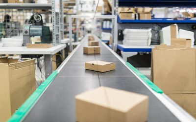 Cardboard boxes on moving belt conveyor at distribution warehouse. Modern warehouse with automatic moving conveyor machine.